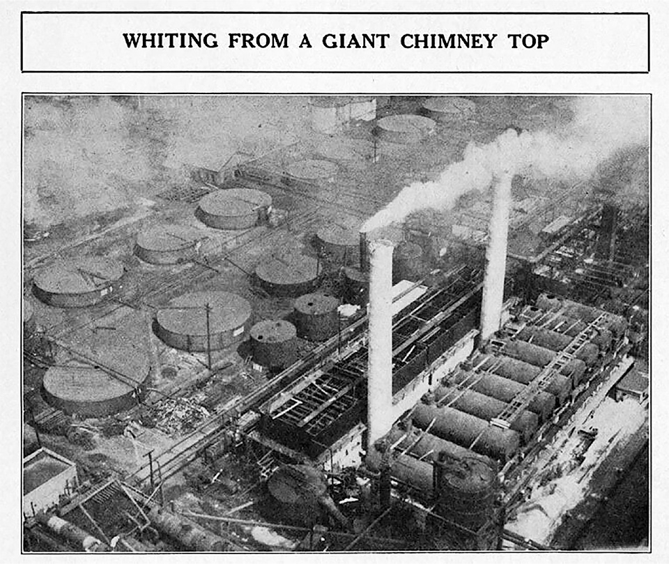 1920 photo o f the refining operations at the Standard Oil Company in Whiting, Indiana; two smokestack billowing exhaust dominate the image, and large tanks for continuous distallation are at the base