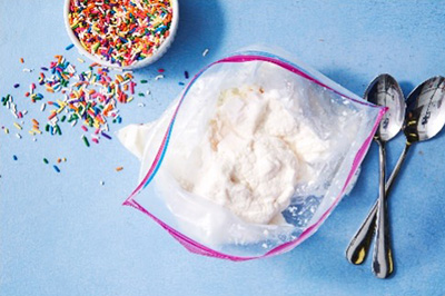 photo of the results of this experiment: a ziplock bag full of home-made ice cream, also showing candy sprinkles and two spoons