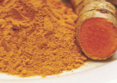 stock photo of turmeric powder next to a root or branch, from which it is presumed the spice originates